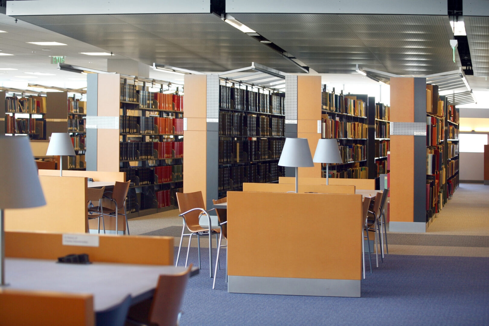 Modern library interior with bookshelves and tables.