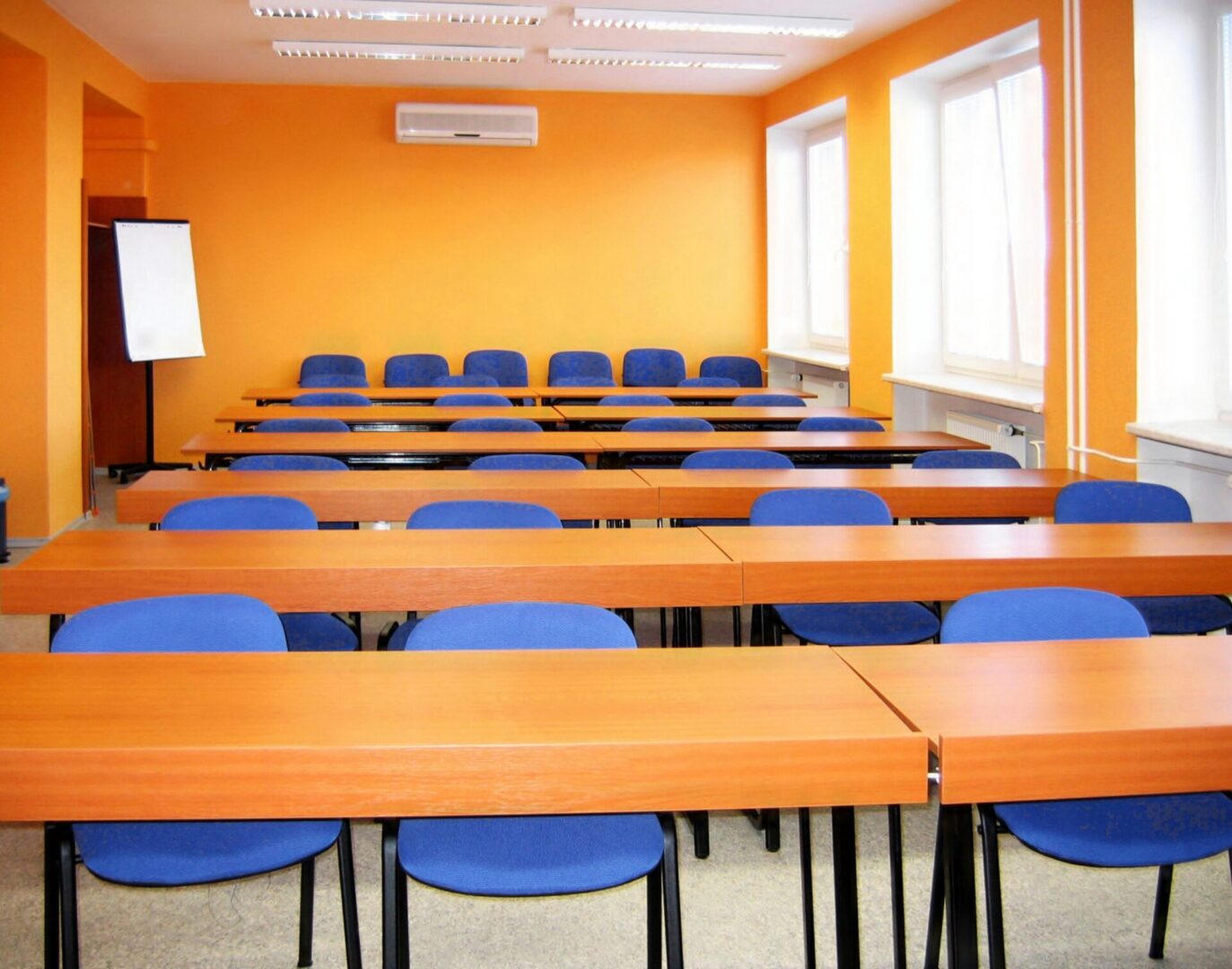 Empty classroom with orange walls and desks.