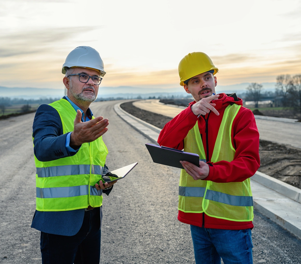 Construction workers discussing road project site.