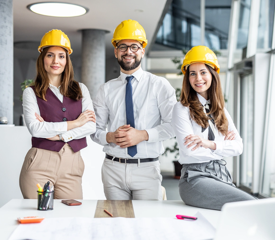 Three architects wearing yellow safety helmets.