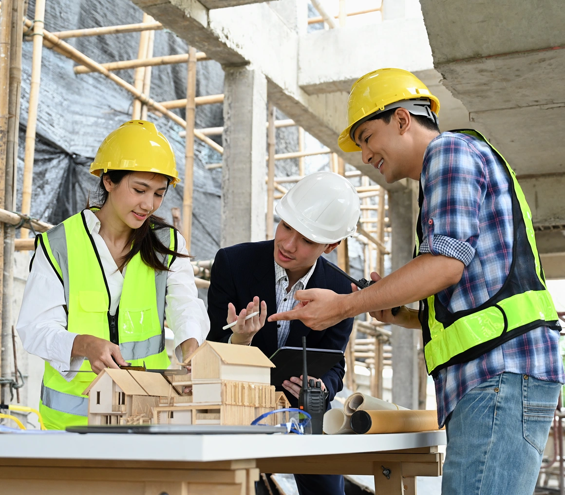 Architects discussing model at construction site.