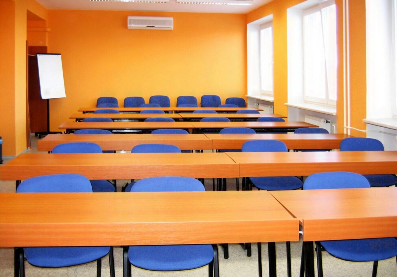 Empty classroom with orange walls and desks.