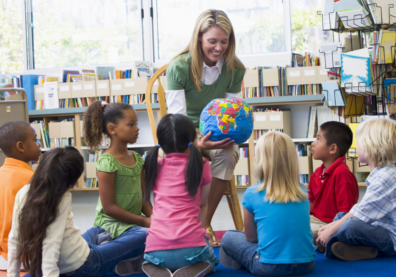 Teacher showing globe to attentive children.
